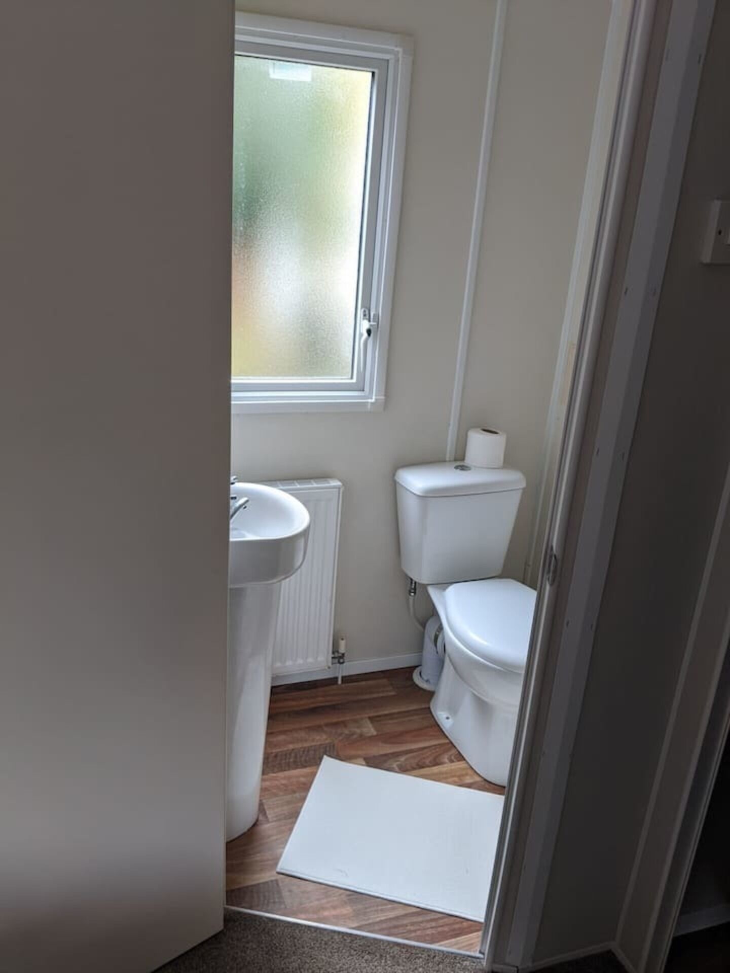 A compact bathroom with a window, a sink, and a toilet.