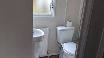A compact bathroom with a window, a sink, and a toilet.