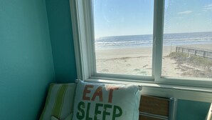 Een kamer met uitzicht op het strand, een bed met een kussen waarop staat 'EAT SLEEP BEACH', en een zeester decoratie.