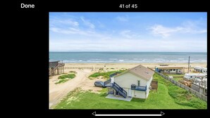 Een pand aan het strand met een huis, een omheind erf en uitzicht op de oceaan.