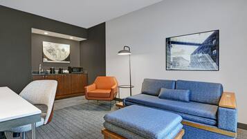 A modern room with a sofa, armchair, and a dining table.