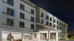 A Courtyard by Marriott hotel with a modern facade, large windows, and a well-lit entrance. - Courtyard by Marriott Hamilton (Robbinsville)