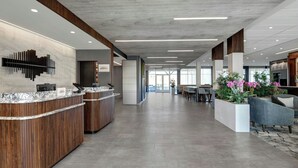 A spacious lobby with a reception desk, seating area, and a view of the outdoors. - Courtyard by Marriott Hamilton (Robbinsville)