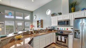Una cocina moderna con encimeras de granito, electrodomésticos de acero inoxidable y muebles de cocina blancos.