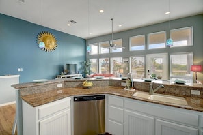 Enjoy cooking in this well-equipped kitchen with a granite countertop, integrated dishwasher, and large window offering a view of the outdoors.