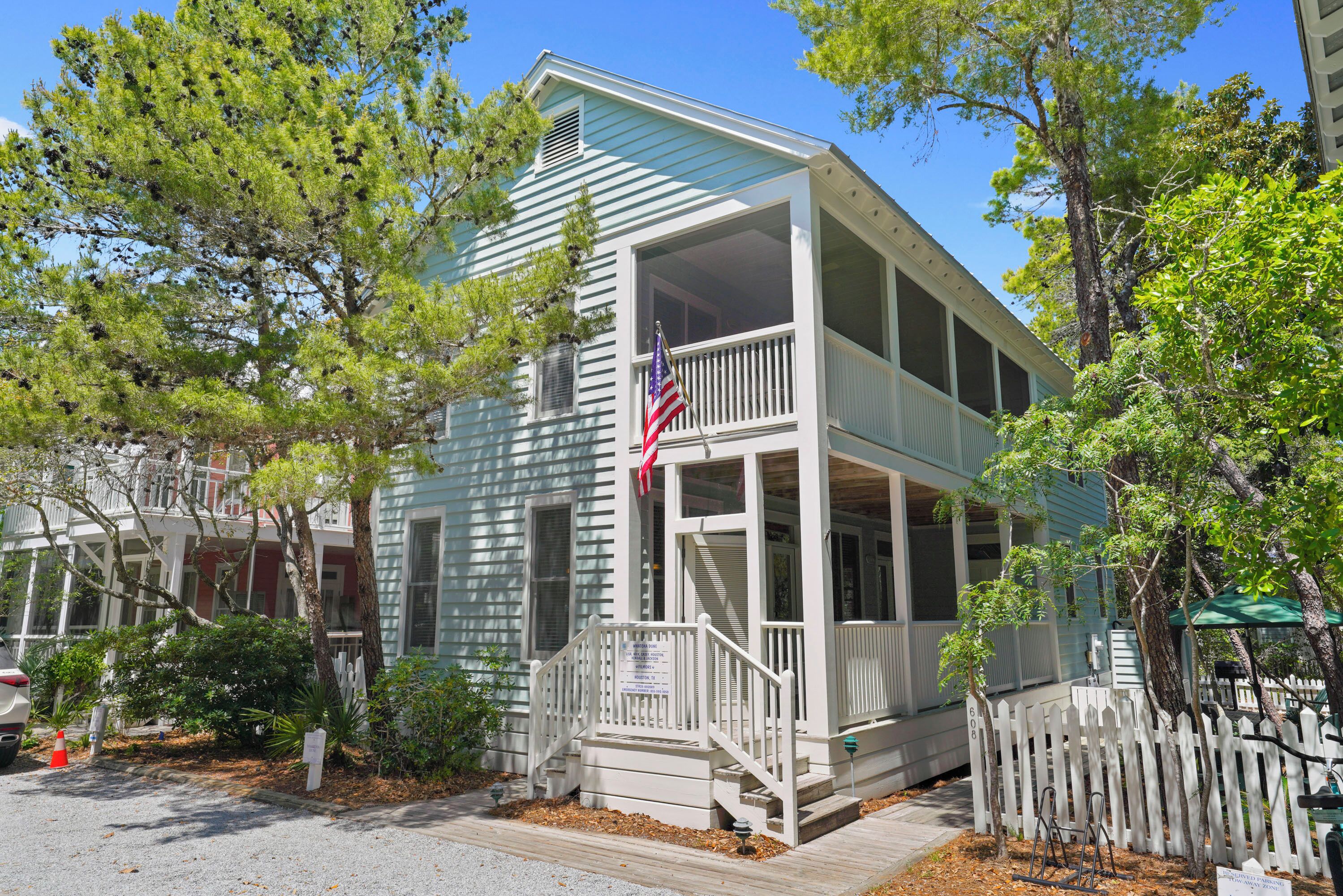 A two-story house with a porch, a flag, and a sign indicating reserved parking.