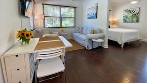 A modern living room with a white sofa, a small table, a desk with a chair, a bed, and a ceiling fan. - 1/1 steps from downtown w/bikes. clean & comfortable (West Palm Beach)