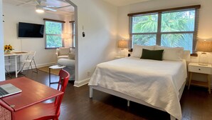 A hotel room with a bed, a desk with a laptop, a chair, a TV, and a ceiling fan. - 1/1 steps from downtown w/bikes. clean & comfortable (West Palm Beach)