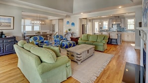 A spacious living area with green sofas, a wooden coffee table, and a dining area with blue patterned chairs. - Relaxing home, just a short walk to the beach and the Intracoastal Waterway (Wrightsville Beach)