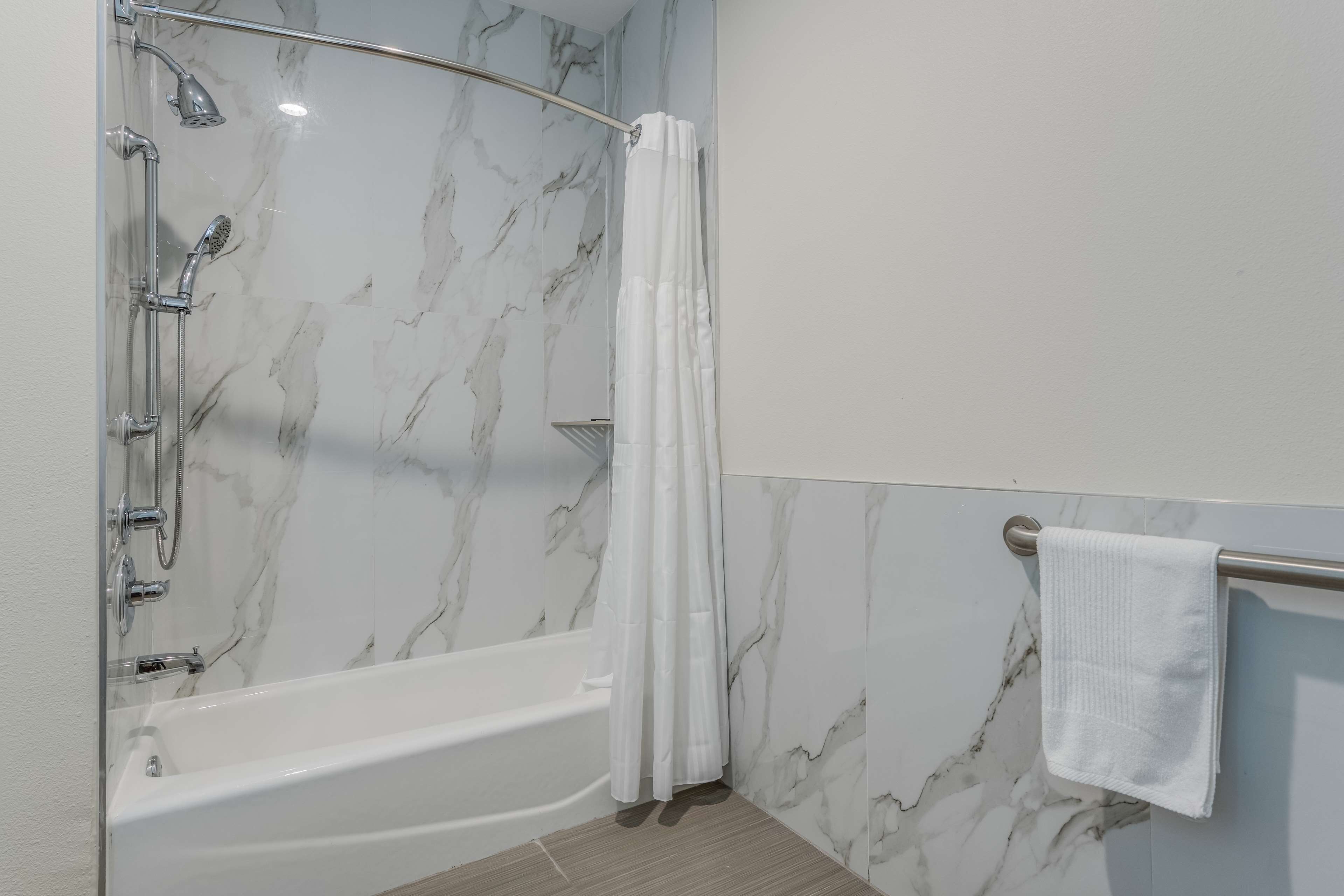 Un baño con bañera, ducha y un perchero para toallas.