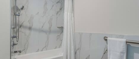 Un baño con bañera, ducha y un perchero para toallas.