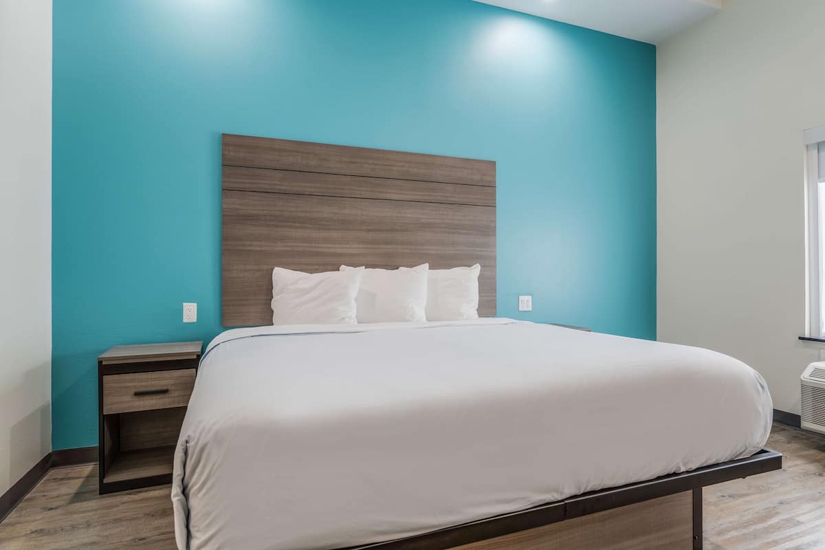 Un dormitorio con cama, mesita de noche y ventana.