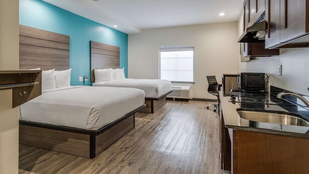 Une chambre d’hôtel avec deux lits, une kitchenette et une fenêtre.