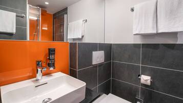Un baño moderno con un lavamanos blanco, inodoro y zona de ducha.