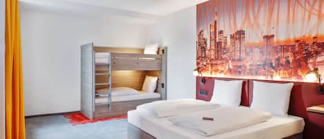 A hotel room with a bed, a bunk bed, a cityscape mural, and a red carpet.