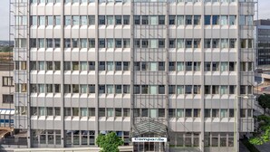 Un edificio moderno con una fachada de ventanas enrejada y una entrada central.