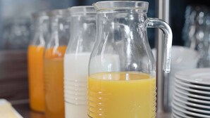 Una jarra de vidrio con jugo de naranja, una jarra de vidrio con leche y una jarra de vidrio con jugo de naranja.