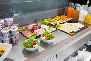 A buffet with various food items including salads, meats, and fruit.