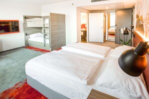 A hotel room with a large bed, a built-in wardrobe, a bathroom with a shower, and a small balcony.