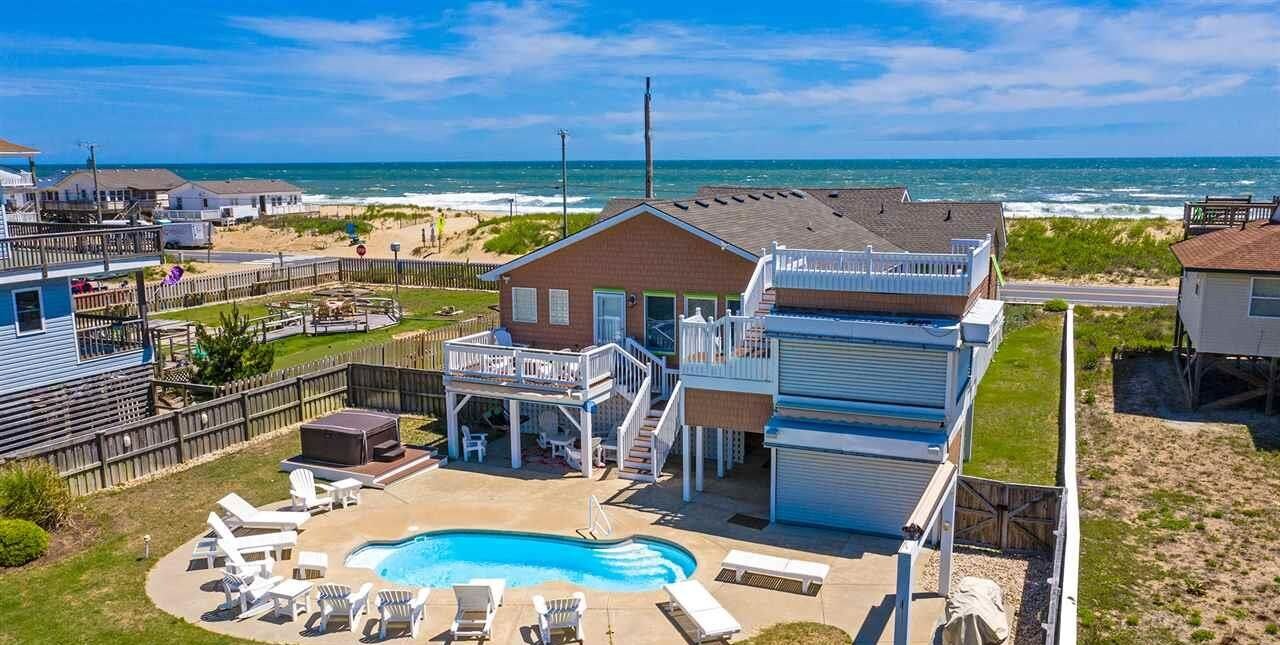 Une propriété située en bord de mer, dotée d’une piscine, de chaises longues et d’une terrasse avec vue sur l’océan.