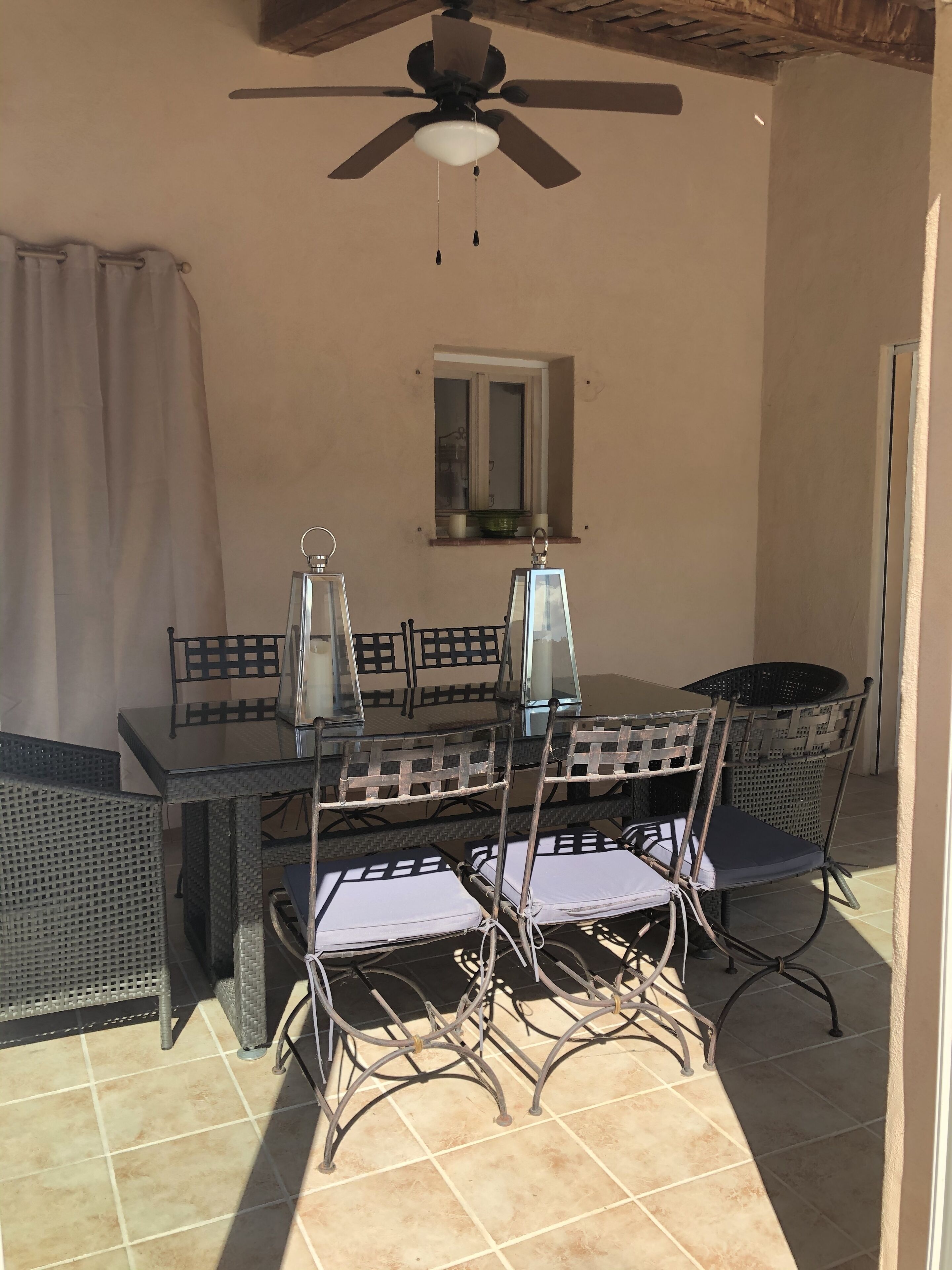 Eine Terrass mit Tisch, Stühlen, Deckenventilator und einem Fenster mit Blick.
