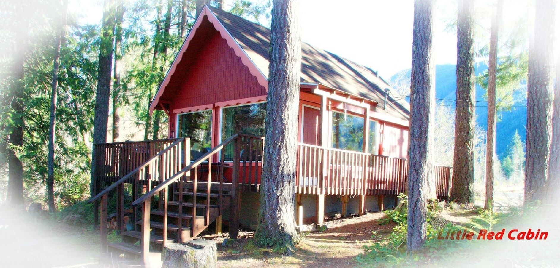 Een chalet met een rood dak, een houten terras en een trap naar een veranda.