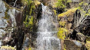 A waterfall cascading over rocky terrain with dense foliage in the background.