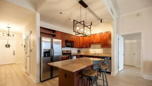 A modern kitchen with wooden cabinets, stainless steel appliances, and a central island with bar stools.