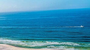 A beach with clear blue water and a boat in the distance.