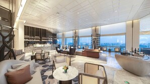 A spacious lounge area with seating, a bar, and large windows offering a city view. - Sofitel Haikou (Haikou)