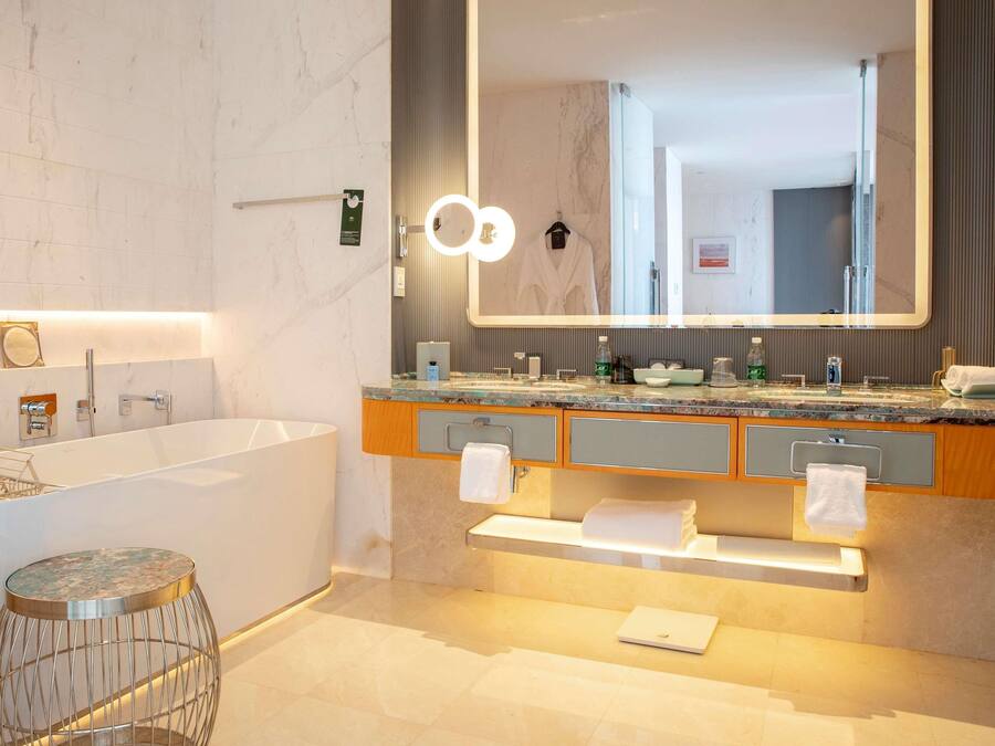 A modern bathroom with a large mirror, a bathtub, and a vanity with a countertop.