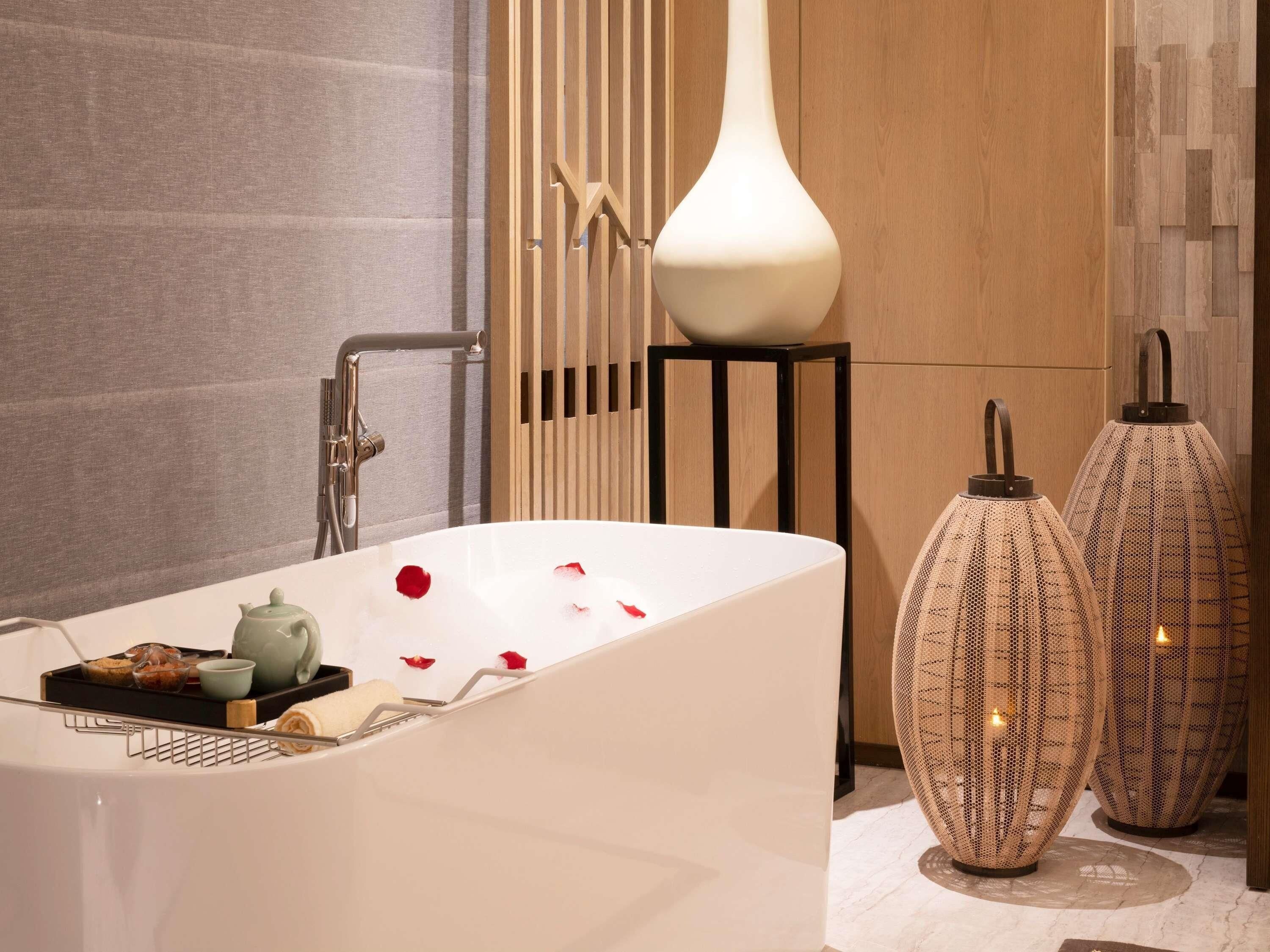 Un baño moderno con una bañera independiente, un perchero y jarrones decorativos.