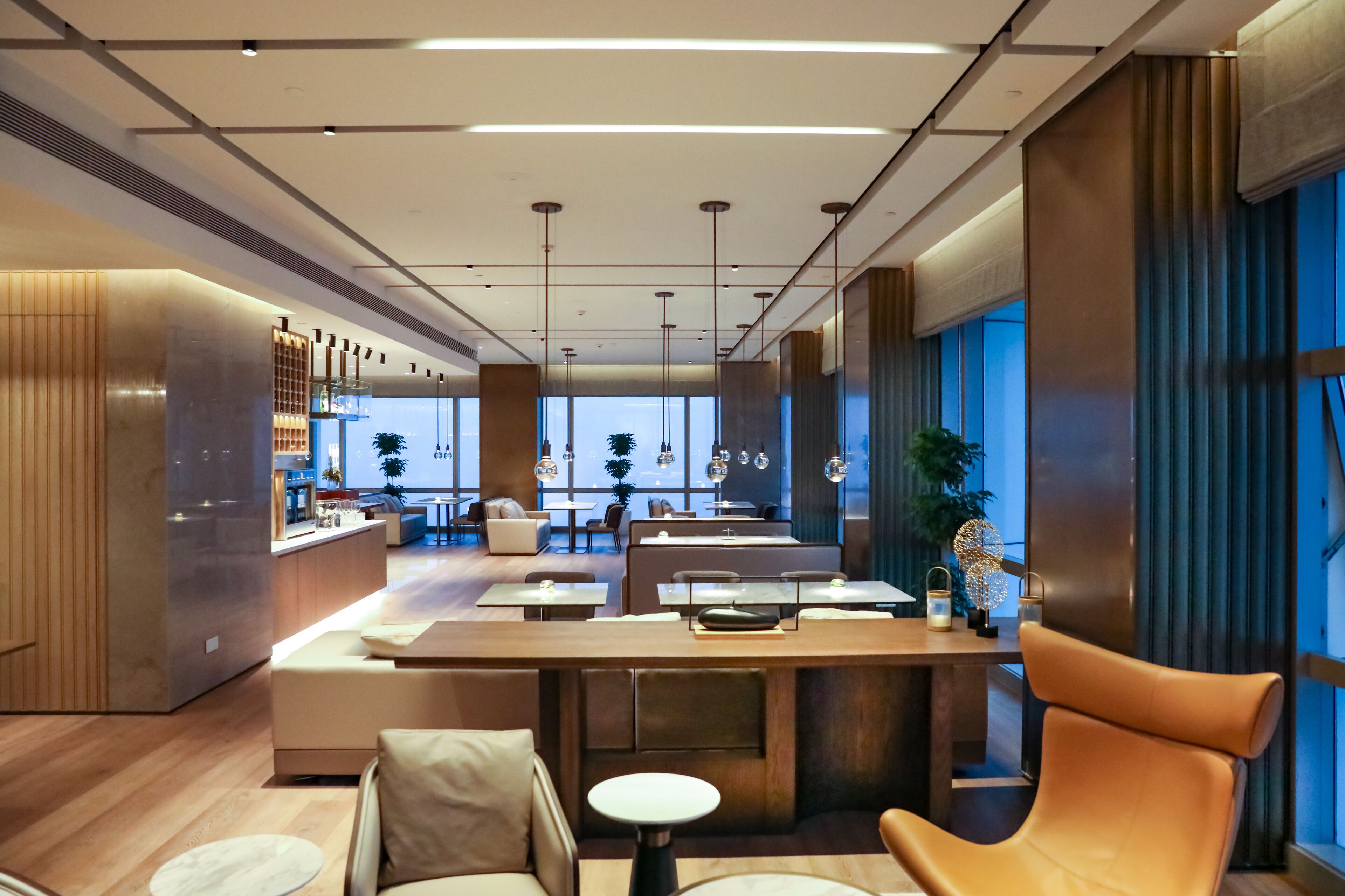 Um hall de hotel moderno com área de estar central, balcão de recepção e grandes janelas.