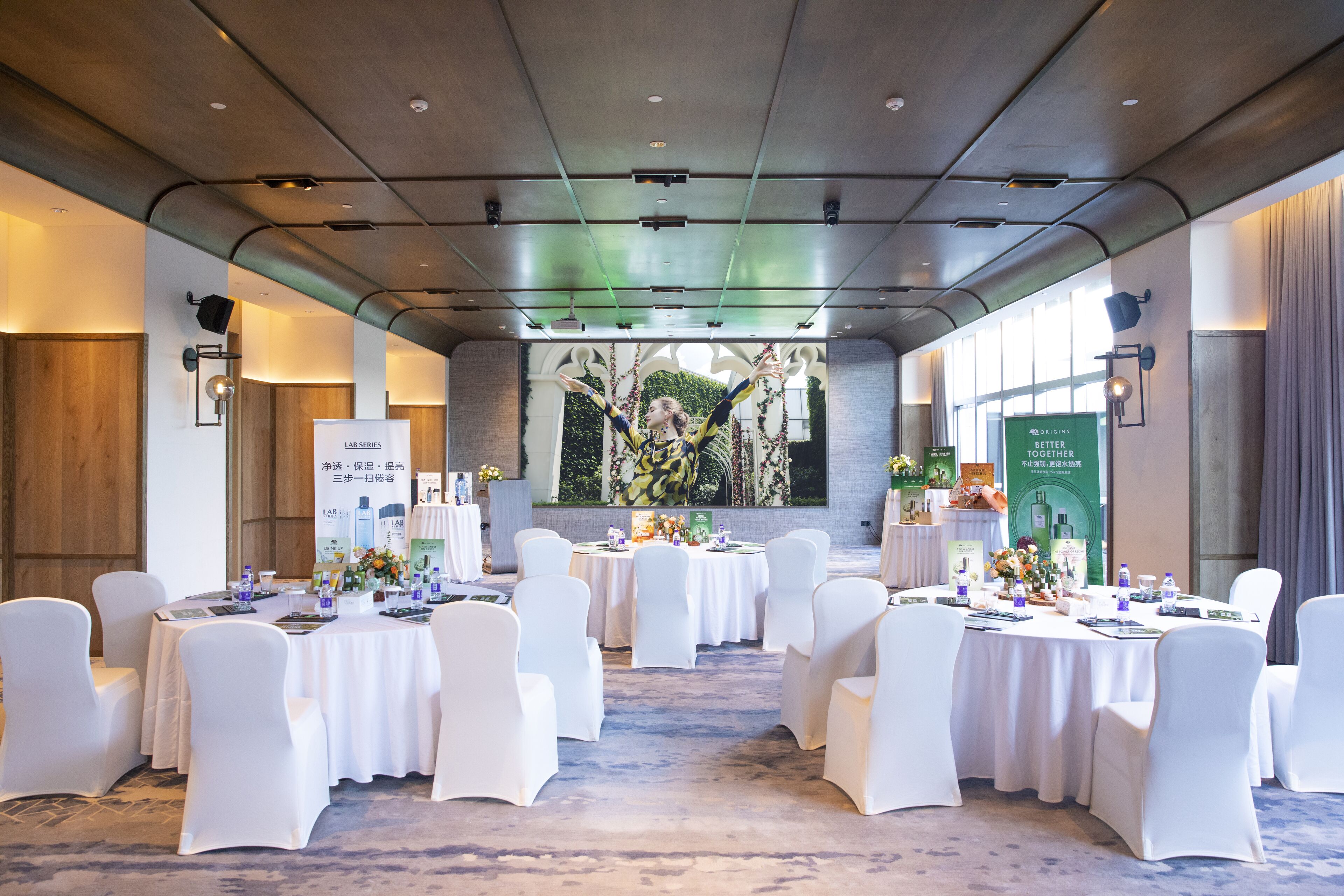 A conference room with round tables, white chairs, and banners.