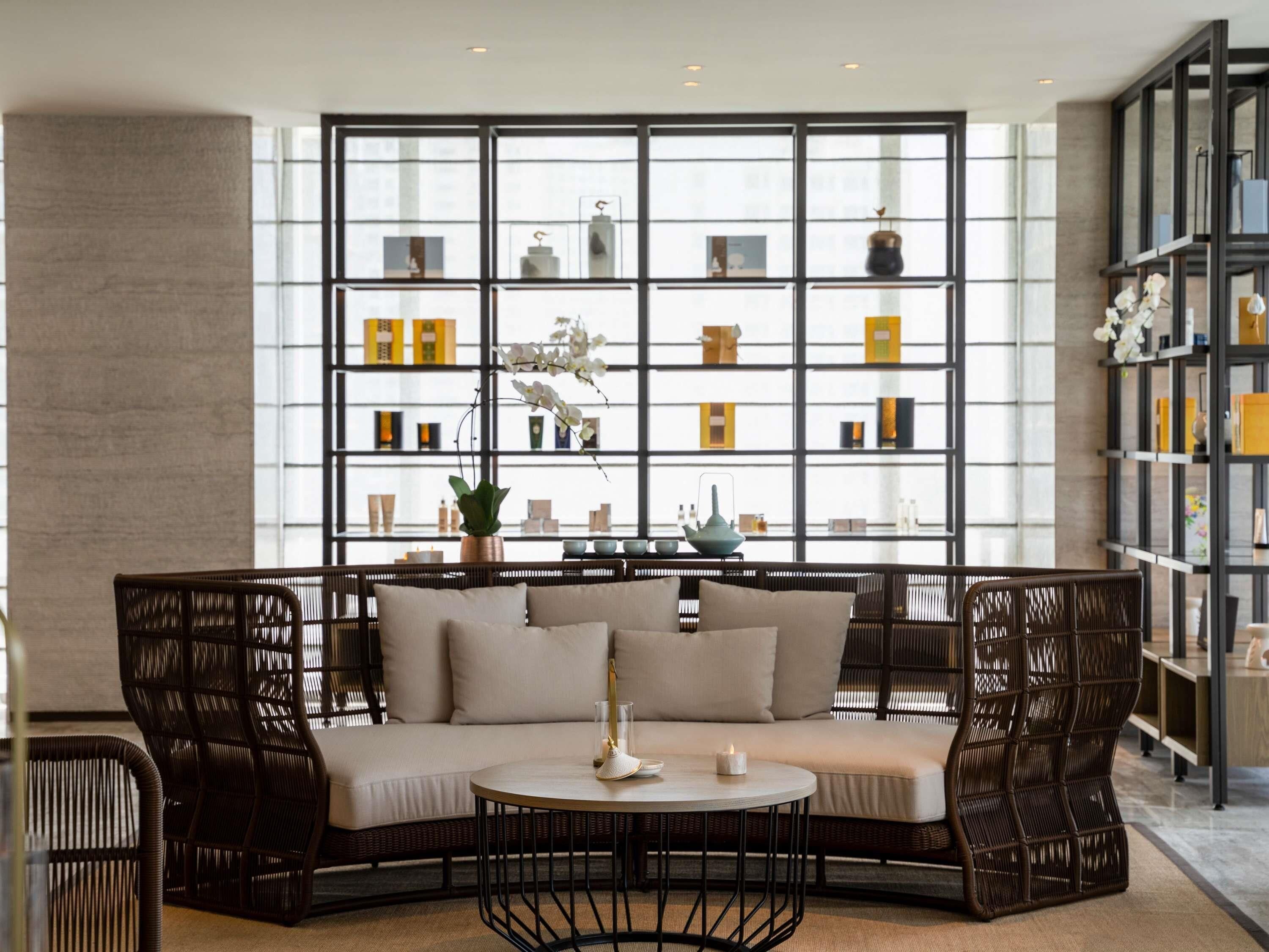 A modern interior with a sectional sofa, a round coffee table, and a large window with a view of the city.