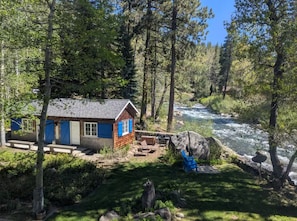 Une cabane avec vue sur la rivière, un espace extérieur aménagé et un grand rocher à proximité.