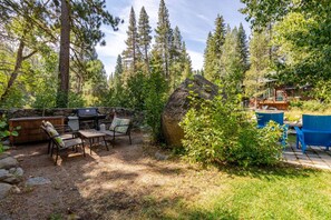 Une terrasse extérieure avec un barbecue, des sièges et un grand rocher.