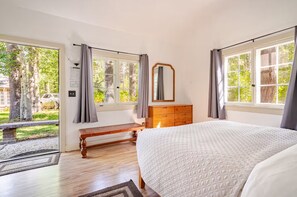 Une chambre à coucher avec un grand lit, une commode en bois, un banc et une fenêtre avec des rideaux.
