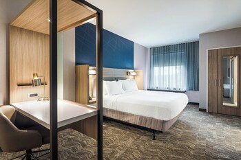 A modern reception area with a curved counter, wooden stools, and a flat-screen TV mounted on the wall. at SpringHill Suites by Marriott Charleston Airport & Convention Center