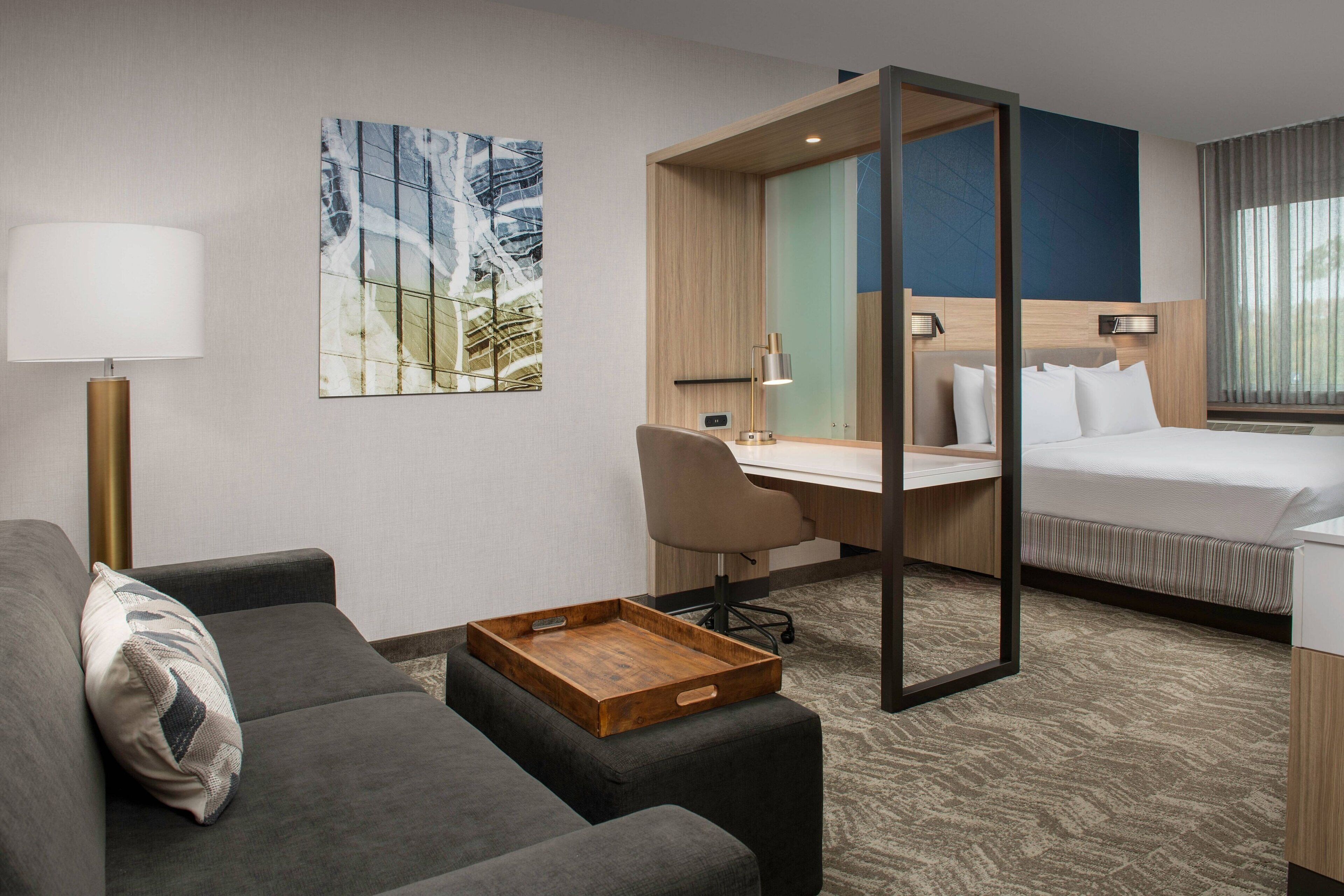 Una habitación de hotel con sofá, escritorio, cama y un amplio ventanal.