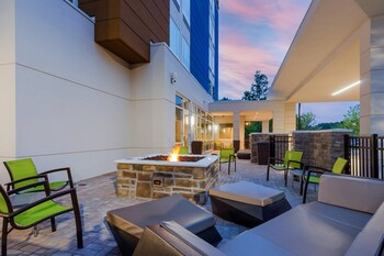A hotel room with a bed, a desk, a chair, a large mirror, and a window with curtains. at SpringHill Suites by Marriott Charleston Airport & Convention Center