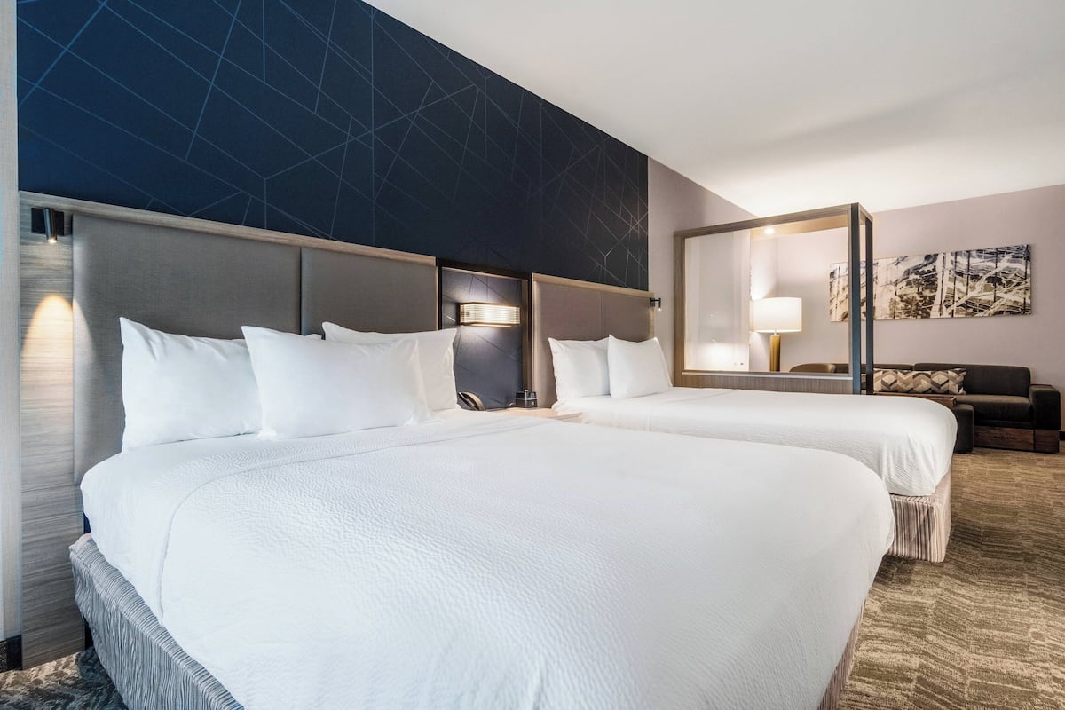 Een hotelkamer met twee bedden, een grote spiegel en een modern wandontwerp.