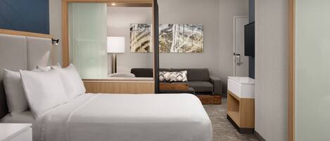 A hotel room with two beds, a sofa, a TV, and a mirror.