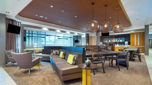 Un moderno vestíbulo de hotel con una zona de estar, un bar y una cocina al fondo.