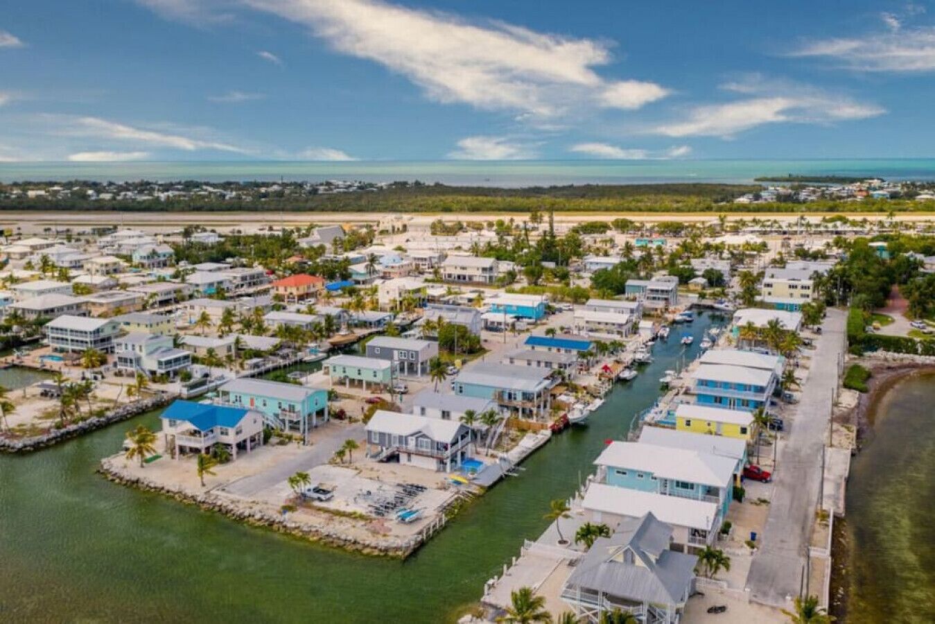 A coastal residential area with houses along a waterway, featuring a marina and a beach.