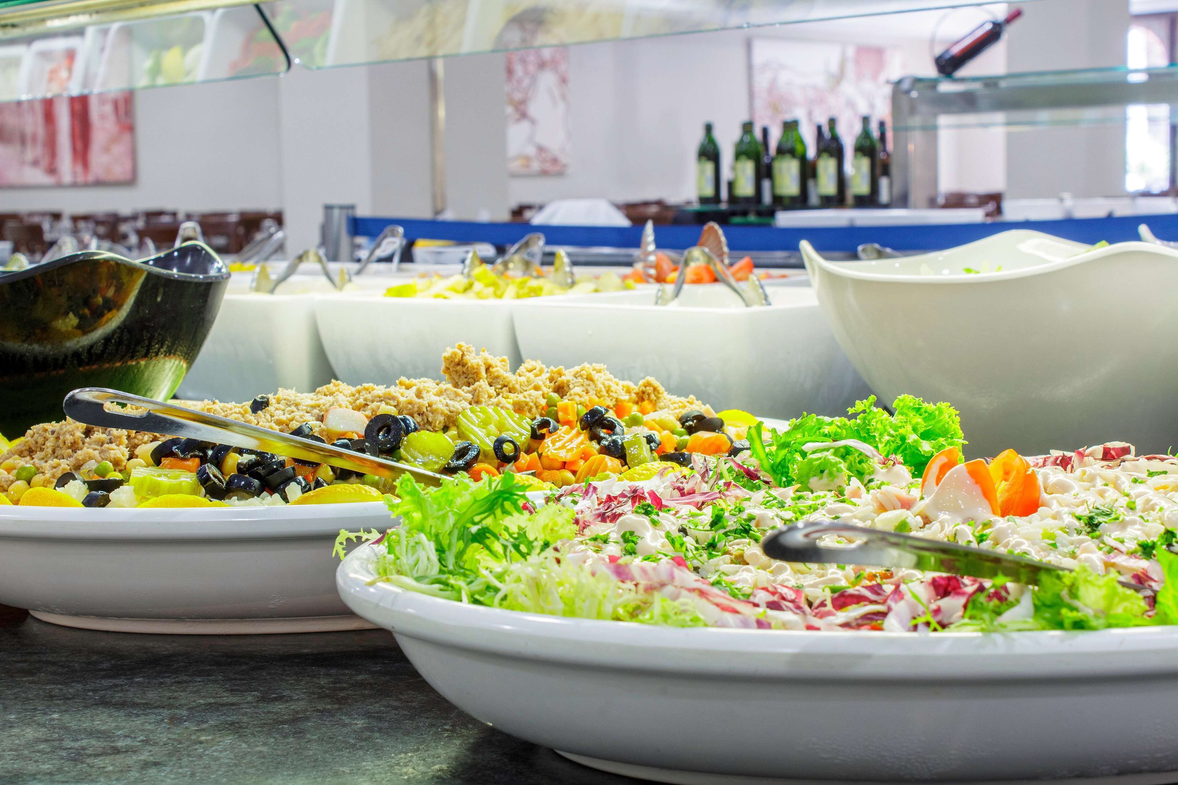 Een buffet met diverse gerechten, waaronder salades en rijstgerechten, gepresenteerd in witte kommen.