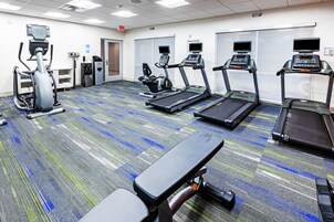 Gimnasio con cintas de correr, elípticas y una banca.