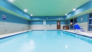 An indoor swimming pool with clear signage, a lifeguard chair, and a pool rule sign.