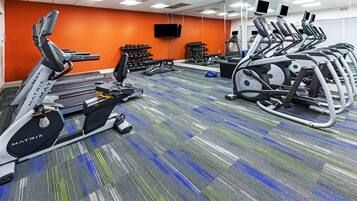 Et fitnesscenter med løbebånd, håndvægte og træningsudstyr.
