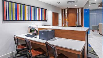 A modern office space with a long reception desk, a colorful abstract painting, and a printer.